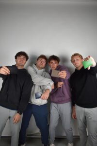 male college students pose with leather wallets they made while studying abroad